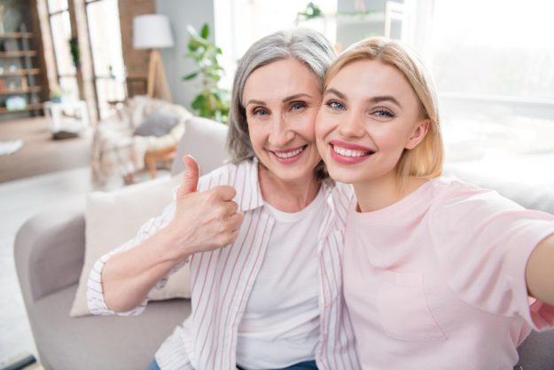 Photo of pretty nice happy woman and young lady hold thumb up smile take selfie indoors inside house home How To Build Strong Relationships With Your Caregivers In West Chester, PA Senior Independent Living