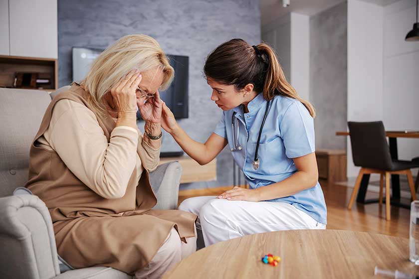 Blond senior woman sitting at home and holding head Blond senior woman sitting at home and holding head