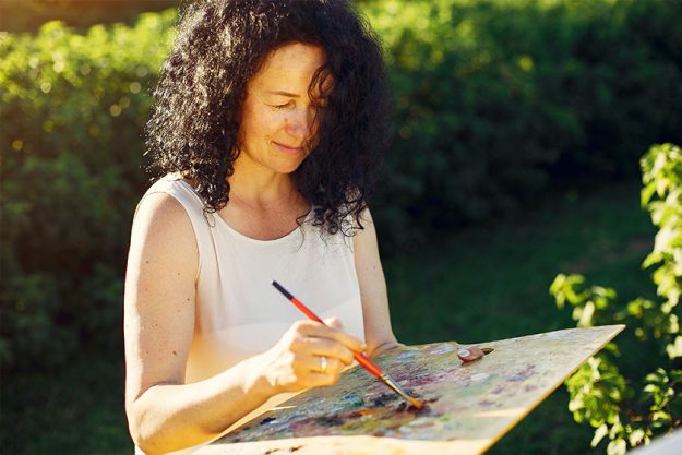 Beautiful adult woman drawing in a summer field Beautiful adult woman drawing in a summer field