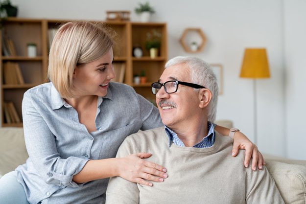 restful-senior-man-his-young-daughter-relaxing-couch-smiling-looking