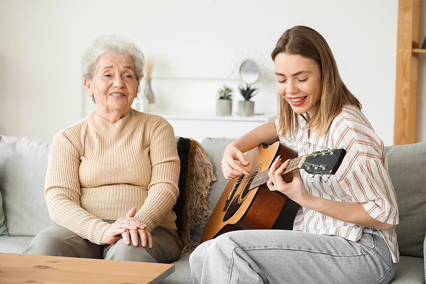 Senior woman and her granddaughter playing guitar home