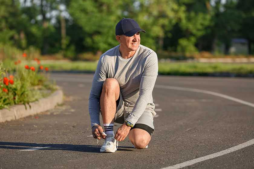 Sporty mature man tying shoe laces on road Sporty mature man tying shoe laces on road