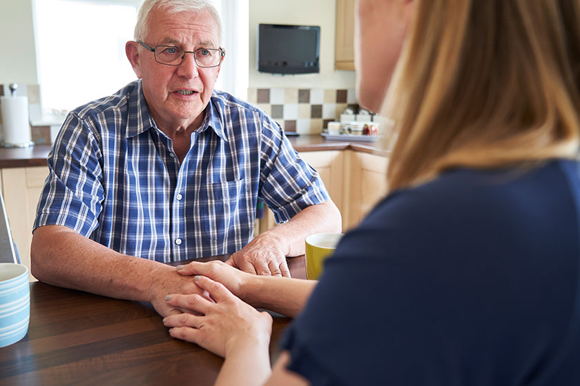 Woman Talking With Unhappy Senior Man Sitting in kitchen at home Woman Talking With Unhappy Senior Man Sitting in kitchen at home