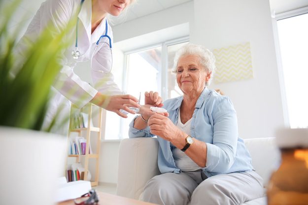 Doctor giving medicine to senior woman at home