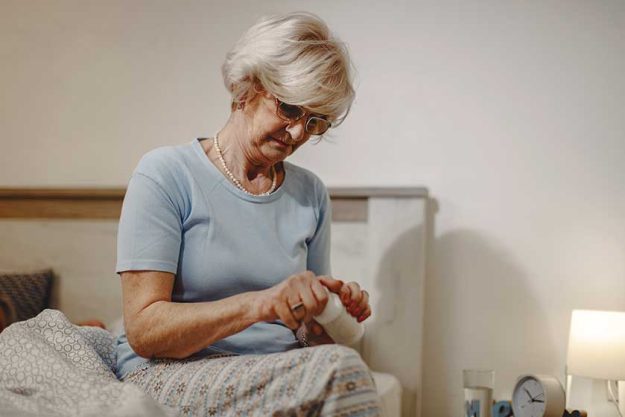Mature woman taking a pill while sitting on the bed at night.