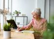 Smiling mature businesswoman writing in notebook while sitting at table in office