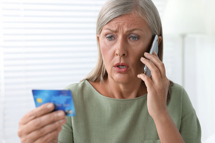 Worried woman with credit card talking on smartphone Worried woman with credit card talking on smartphone