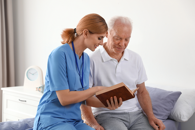 Nurse reading book to elderly man
