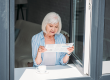 Senior woman standing at windowsill with cup