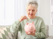 Senior woman putting money in piggy bank