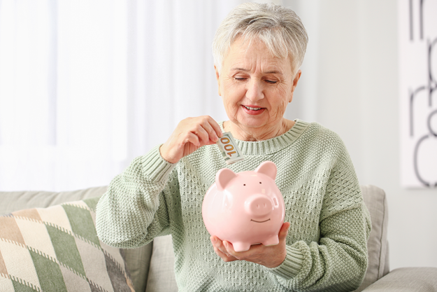 senior-woman-putting-money-piggy-bank Senior woman putting money in piggy bank